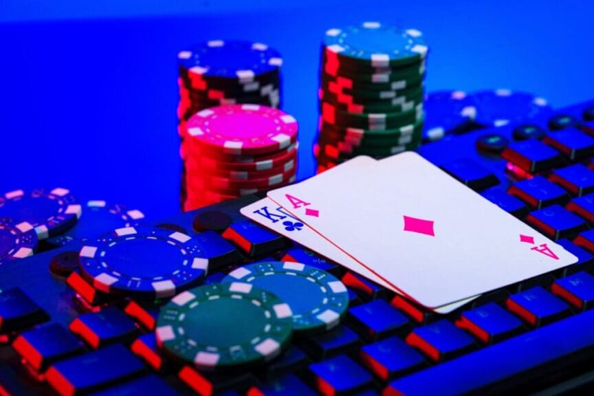 Close-up of playing cards and poker chips on a keyboard, illuminated with colored lighting